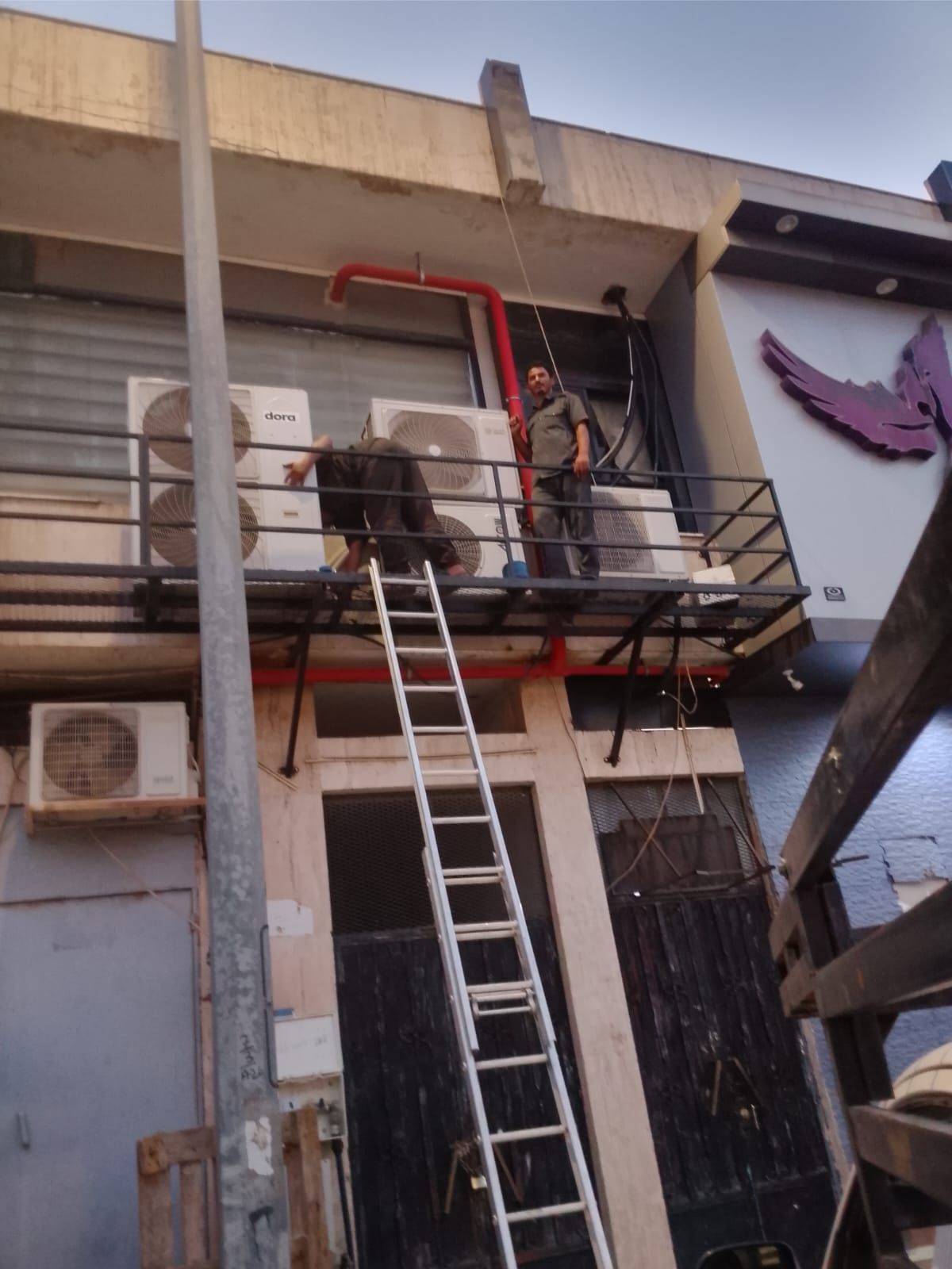 فنيو تكييف يقومون بتركيب وحدات سبليت على واجهة معرض تجاري بالطائف
